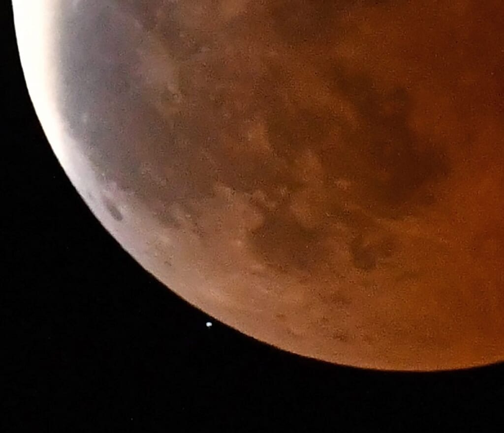 赤黒く輝く月、雲間からちらり　皆既月食と天王星食に歓声